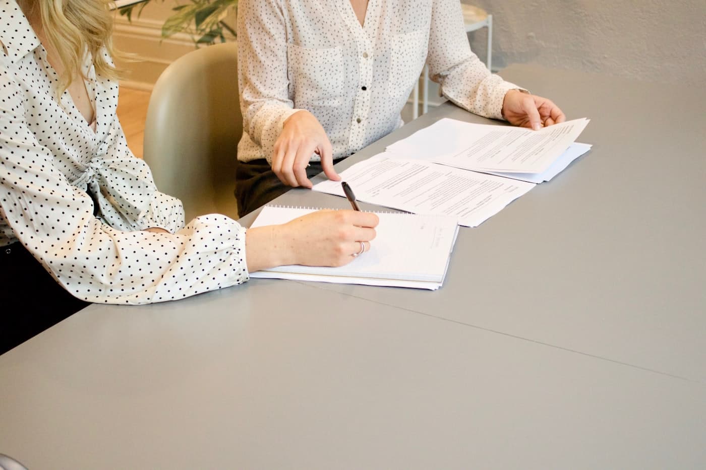 Deux personnes annotent un jeu de documents imprimés posé sur une table de réunion